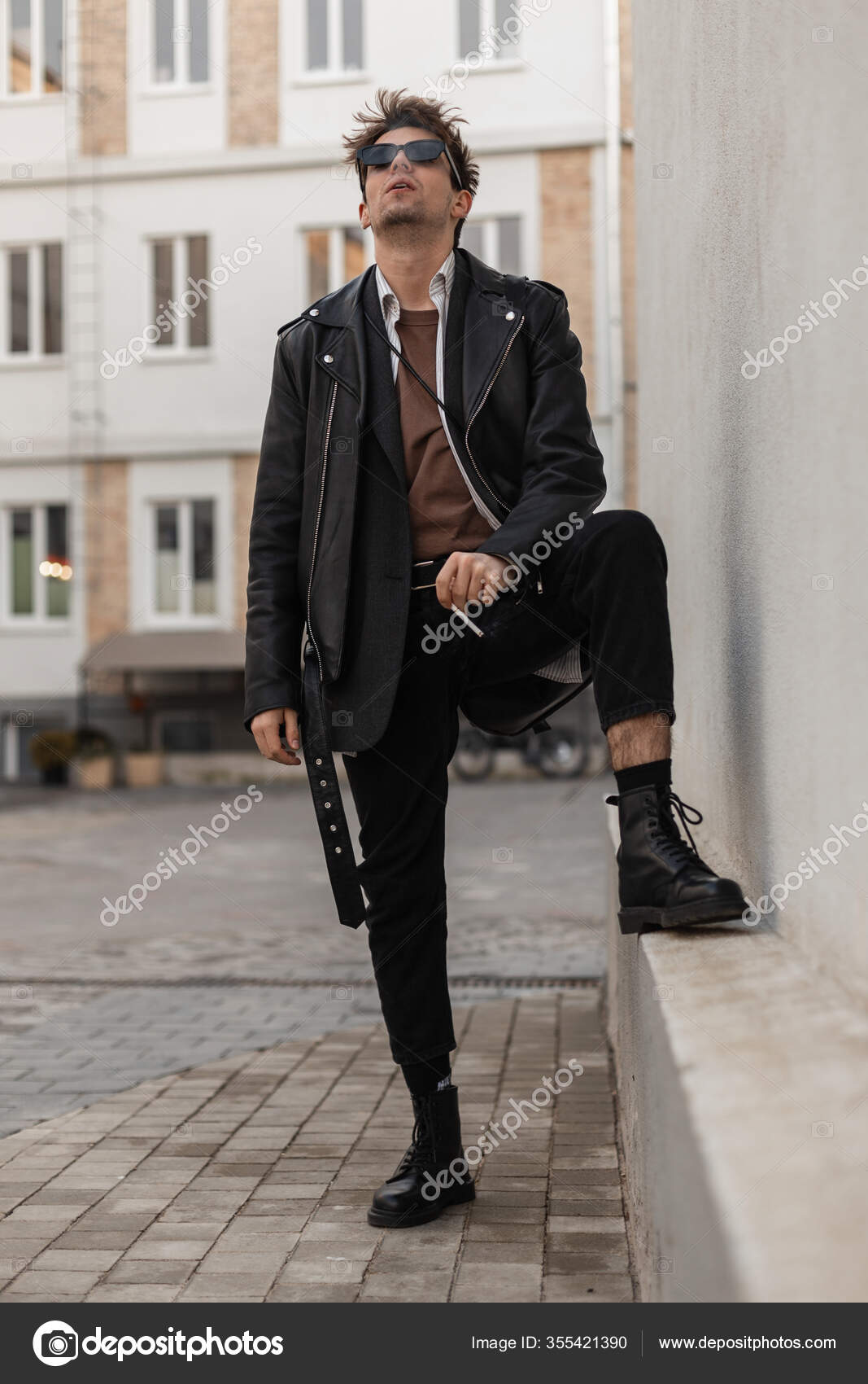 Chico joven guapo con estilo con una máscara protectora médica y gorra negra  en ropa de moda con una chaqueta y una sudadera con capucha en la calle.  moda y estilo urbano