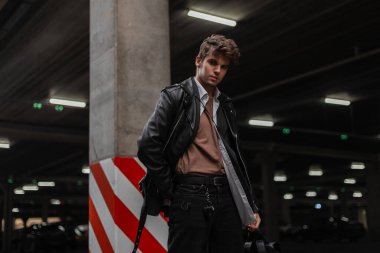 Amerikan tarzında genç, profesyonel, havalı bir adam. Deri bir sırt çantası ve son moda saç stili var. Sokakta dinleniyor. Yakışıklı şehir çocuğu, dışarıda poz veren manken..