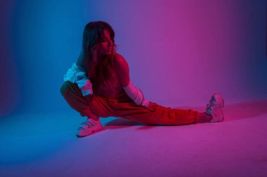 Moda ayakkabılı, modaya uygun kadın dansçı çok renkli neon renklerle dolu bir odada eğitim görüyor. Çekici kız içeride şık pembe bir ışıkla fitness yapıyor..