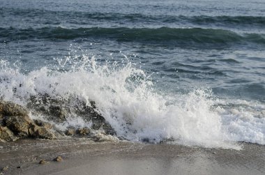 Sahilde dalgalar yükseliyor ve uzun kepenklerle düzeliyor.