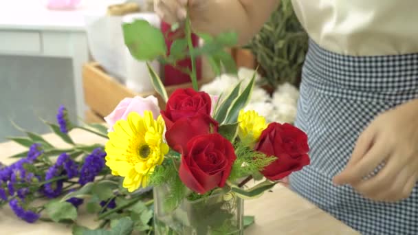 Florista mulher cortando flores e arranjando belas flores em um vaso de vidro — Vídeo de Stock