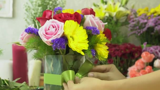 Florist woman finished to arranging flowers with tying ribbon on a glass vase — Stock Video