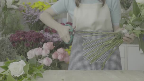 Dolly shot of florist woman trimming stems of white flowers, ungraded tone — Stock Video