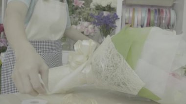 Çiçekçi kadın güzel bir çiçek buketi, derecelendirilmemiş sesi kurdele bağlama