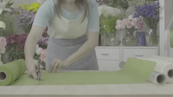 Доллі знімок флориста готує папір, щоб обгорнути букет, немодернізований тон — стокове відео