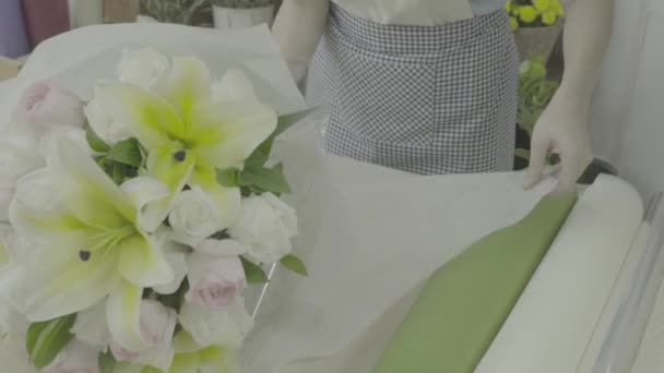 Florista mujer envolviendo un ramo de flores con papel, tono sin graduar — Vídeos de Stock