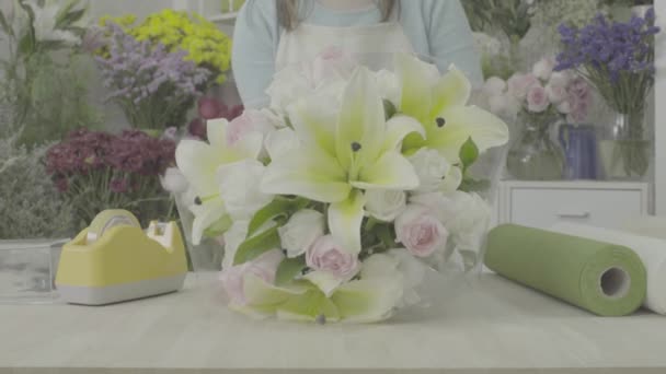 Dolly tiro de florista mujer envolviendo un ramo de flores con papel, tono sin graduar — Vídeo de stock