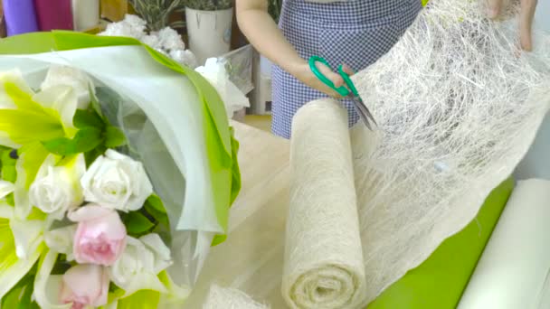 Dolly tiro de florista mujer corte de papel para envolver un ramo de flores — Vídeos de Stock