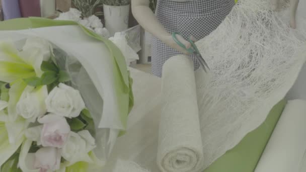 Dolly shot of florist woman cutting paper to wrapping a bouquet, ungraded tone — Stock Video