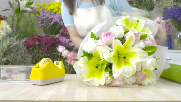 Dolly Shot von Blumenhändlerin, die einen Blumenstrauß mit Papier umwickelt — Stockvideo