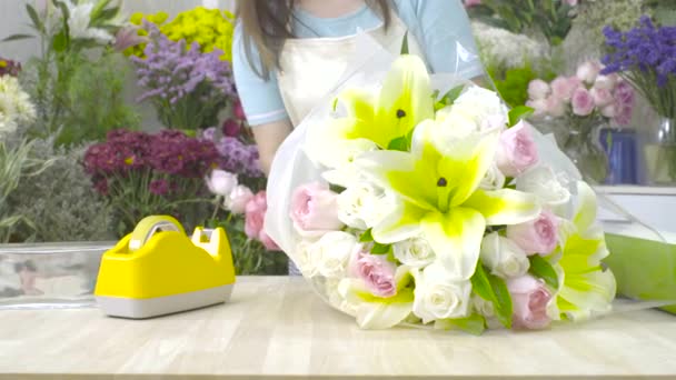 Dolly shot of florist woman wrapping a flower bouquet with paper — Stock Video