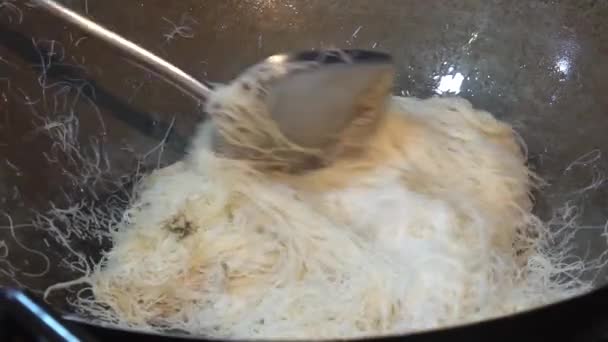 Yellow noodles are being fried in hot frying pan in slow-motion — Αρχείο Βίντεο