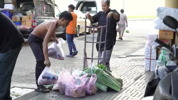 Kooplieden sorteren van vers voedsel dat hij onlangs van de opslag aan zijn winkelwagen gekocht — Stockvideo