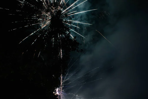 fireworks and artificial games in the night behind a tree and a church