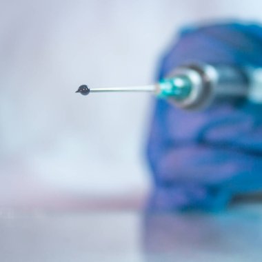 Şırıngada mavi eldiven kullanılarak kovid 19 tedavisi için bir aşı damlası bulundu.