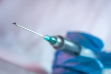 Şırıngada mavi eldiven kullanılarak kovid 19 tedavisi için bir aşı damlası bulundu.