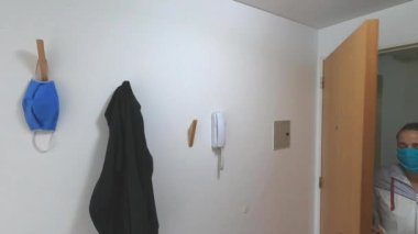 Kadın eve gelir ve maskesini takar.