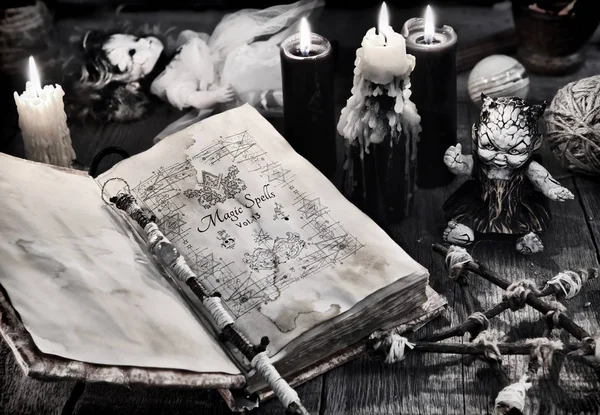 Old book with black magic spells, scary doll, black candles and pentagram. Halloween, occult, esoteric and wicca concept. Vintage background