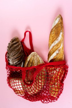 Lezzetli taze ekmekle örülü alışveriş torbası. Pembe arka planda ekmekten yapılmış özel tasarım eko çantanın yemek fotoğrafları.