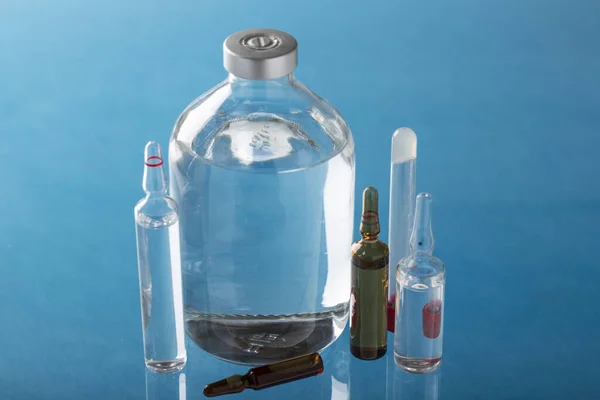 青い背景に注射瓶と薬瓶 — ストック写真