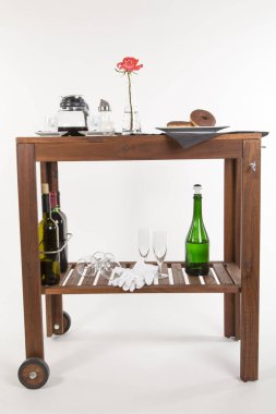 Alkol şişeleri ve beyaz arka planda gül olan ahşap masa.