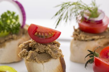 Taze sebzelerle süslenmiş ekmek üzerine ciğer sosisi.