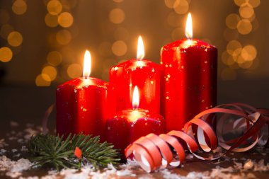 Eski ahşap arka planda kırmızı mumlar ve noel ışığı perdesi.