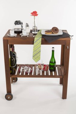 Alkol şişeleri ve beyaz arka planda gül olan ahşap masa.