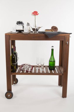 Alkol şişeleri ve beyaz arka planda gül olan ahşap masa.