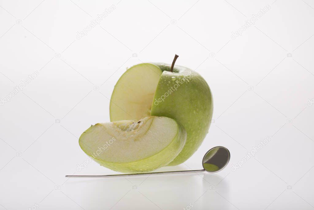 dental speculum with green apple, as  symbol of tooth health