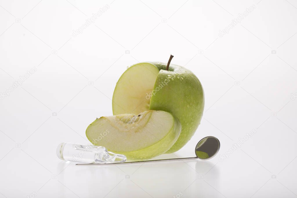 dental speculum with green apple, as  symbol of tooth health