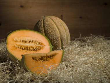 Eski ahşap arka planda saman üzerinde kavunlar