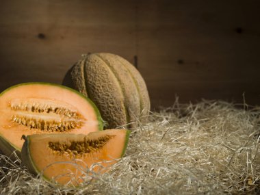 Eski ahşap arka planda saman üzerinde kavunlar