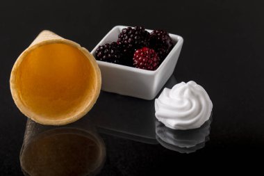 Bir kase krem şantili dut ve koyu arkaplanda dondurma.