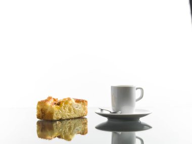 Bir fincan kahve yansıtıcı yüzeyde bir parça turta.