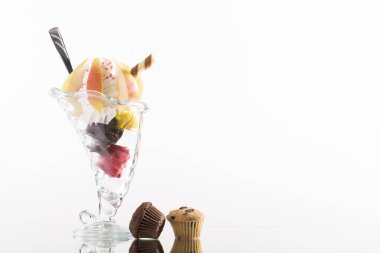 Beyaz arka planda krem şanti ile süslenmiş renkli armut sundae.