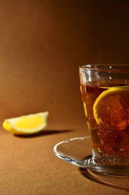 Kahverengi arka plan dikey yönelimli çay ve limonlu cam bardak