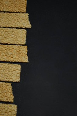 Mısır gevreği waffle ekmeği sol kenarda yukarıdan siyah arkaplan görünümünde ve dikey bir kopya alanı yönelimi ile