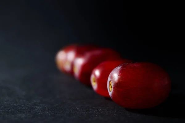 red grape berries in a row on a black background with copy space horizontal orientation