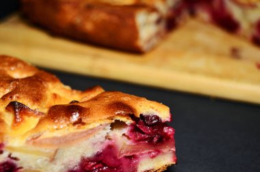 Siyah arka planda elmalı ve vişneli kek.