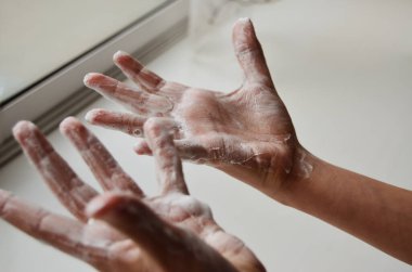 Çocukların şişmiş elleri beyaz pencerenin arka planında sabunla yıkanmış.