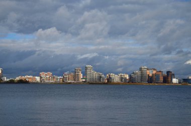 Şehrin yüksek binalarının ufuk çizgisinde nehir ve bulutlar var.