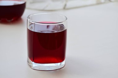Pencerenin yatay yöneliminde kuşüzümü suyu olan cam bardak