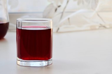 Perdeleri olan beyaz bir pencere pervazında üzümlü su.