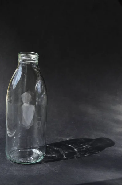 Стеклянная Бутылка Черном Фоне Отбрасывает Тень Игры Солнечных Лучей — стоковое фото