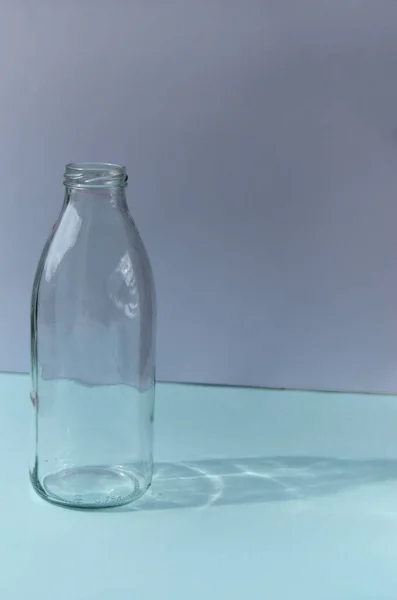 Üvegpalack Áll Egy Kék Asztal Hátterében Egy Fehér Fal Árnyék — Stock Fotó