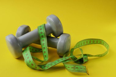 Sarı arka planda ince bel sporunu ölçmek için kurdeleye sarılmış aptallar.