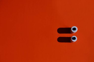 Beyaz dikiş ipliği olan iki bobin ve fotokopi alanı olan turuncu arkaplana gölge düşür.