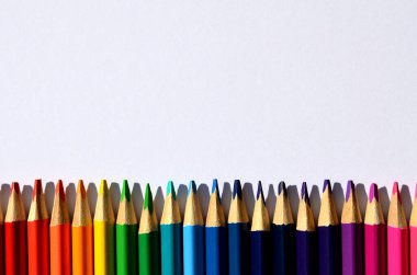 Renkli kalemler beyaz bir arkaplan üzerinde bir çerçeve gibi dizilmiştir.