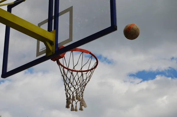 Football flies to the basketball ring against the cloudy gray sky — Stock Photo, Image